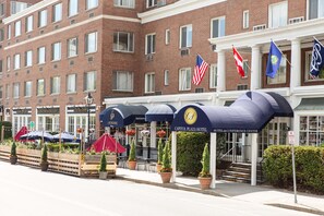 A hotel with a brick facade, American flags, and a sign for the Capitol Plaza Hotel.