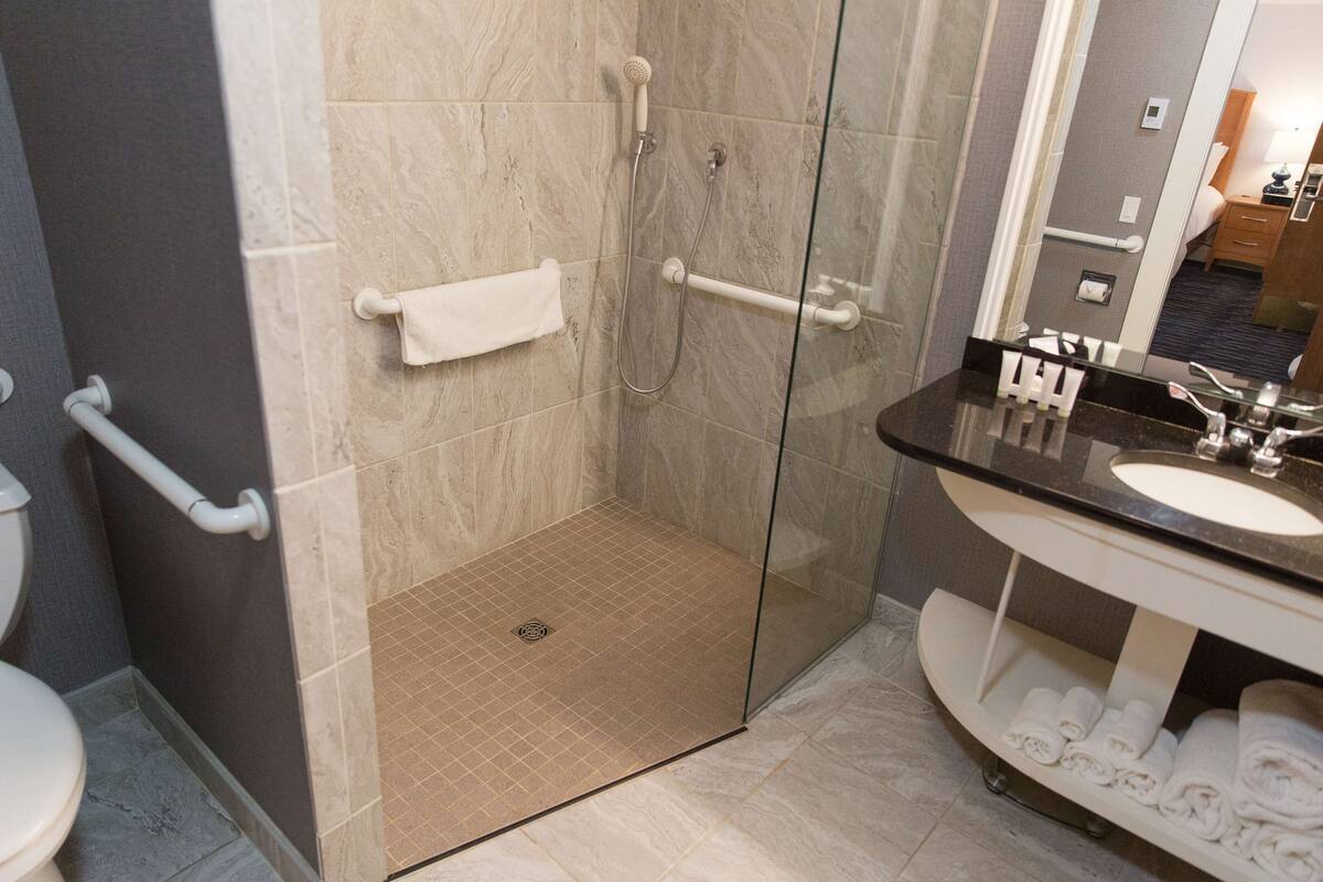 A modern bathroom with a glass-enclosed shower, a white sink, and a vanity with towels.