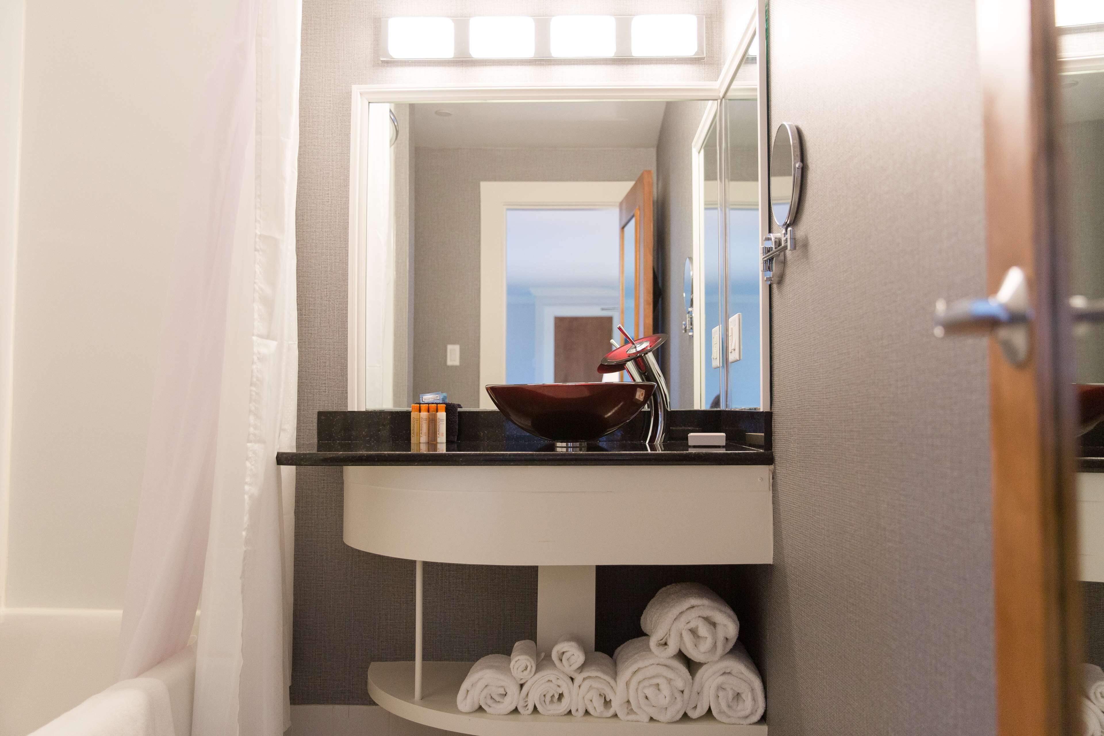 A bathroom with a white sink, a mirror, and a towel rack.