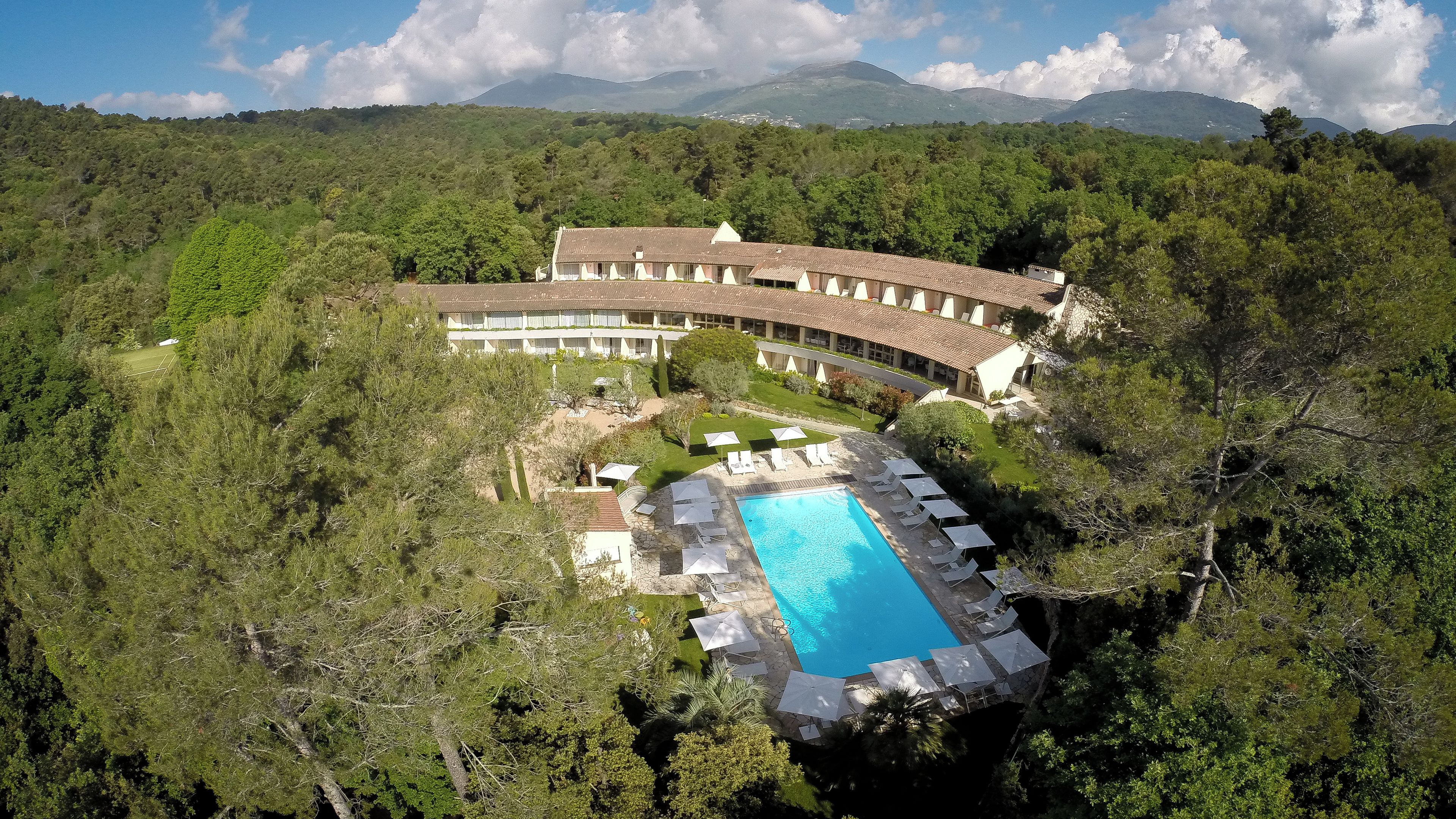 Un complexe hôtelier doté d’une piscine, de nombreuses chambres et entouré d’un paysage luxuriant.