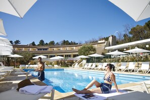 Una piscina al aire libre de temporada, sombrillas