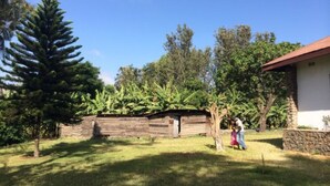 A rustic wooden structure with a stone wall, surrounded by lush greenery and trees.