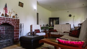 A living room with a fireplace, two armchairs, a sofa, and a wooden bench.
