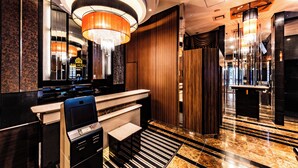 A modern hotel lobby with a reception desk, a large chandelier, and a marble floor. - APA Hotel Ginza Shintomicho Ekimae (Tokyo)