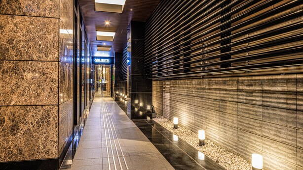 A corridor with a marble wall, a wooden slatted wall, and a sign for the "AIA HOTEL". - APA Hotel Ginza Shintomicho Ekimae (Tokyo)