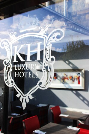 Un logo de « KH Luxury Hotels » sur une fenêtre.