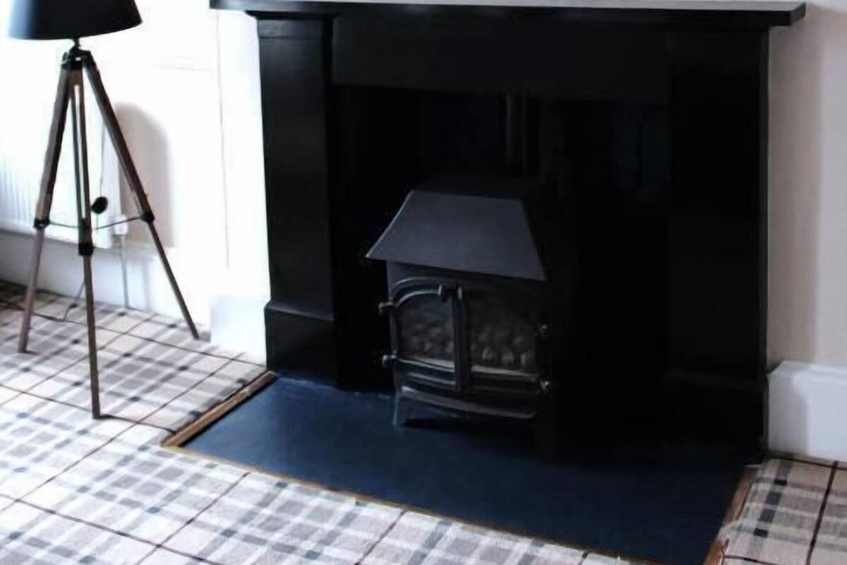 Una habitación con chimenea, televisión instalada y una lámpara con trípode.