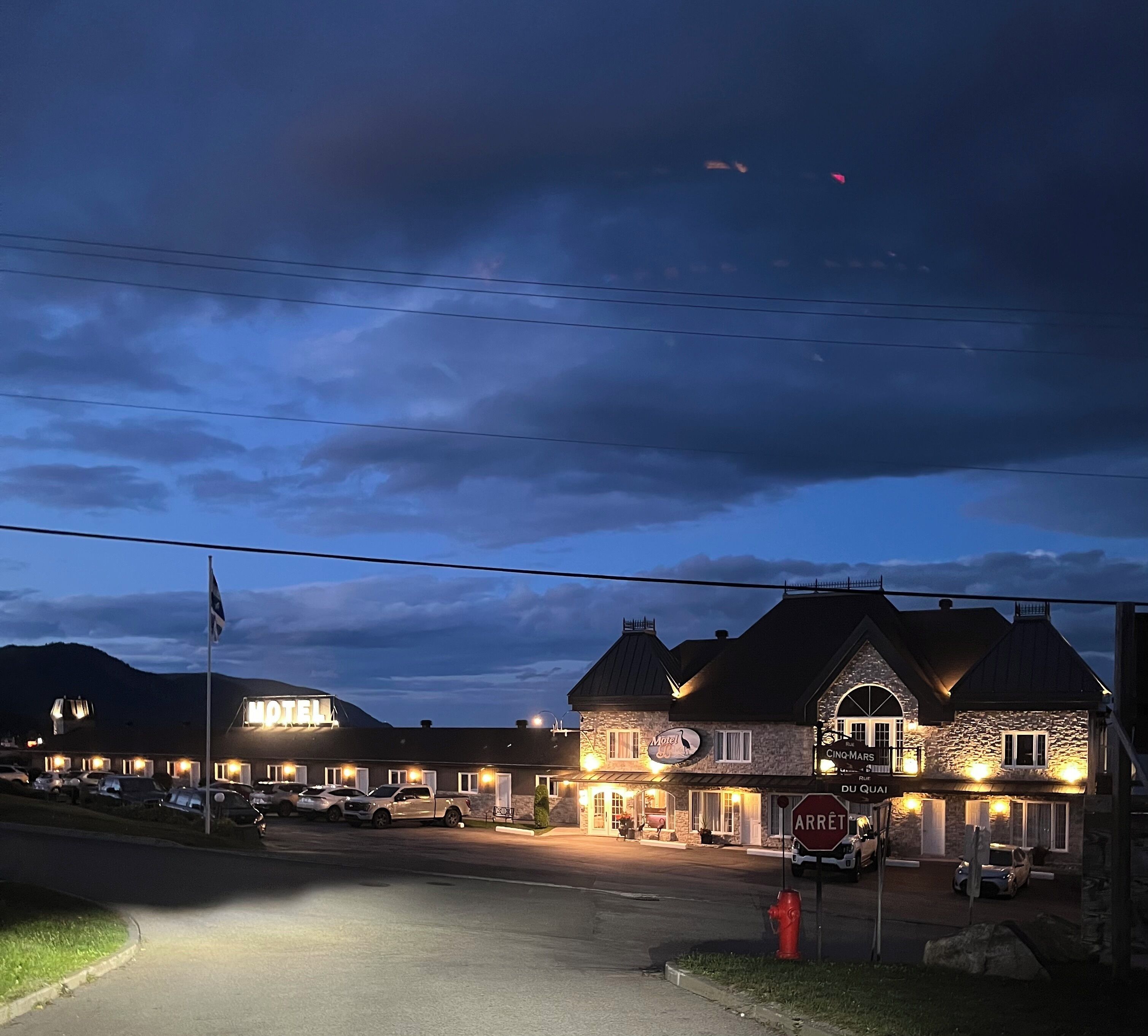 Un motel con fachada de piedra, varias habitaciones y un estacionamiento.