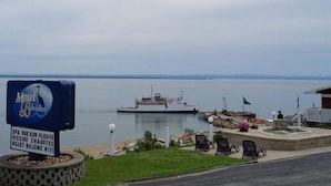 Vista de um corpo d'água com um barco atracado em um marina, um letreiro do Motel Belvédère e um pequeno edifício com área externa para sentar.