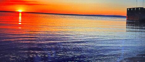 A sunset over a calm body of water with a pier extending into the water.