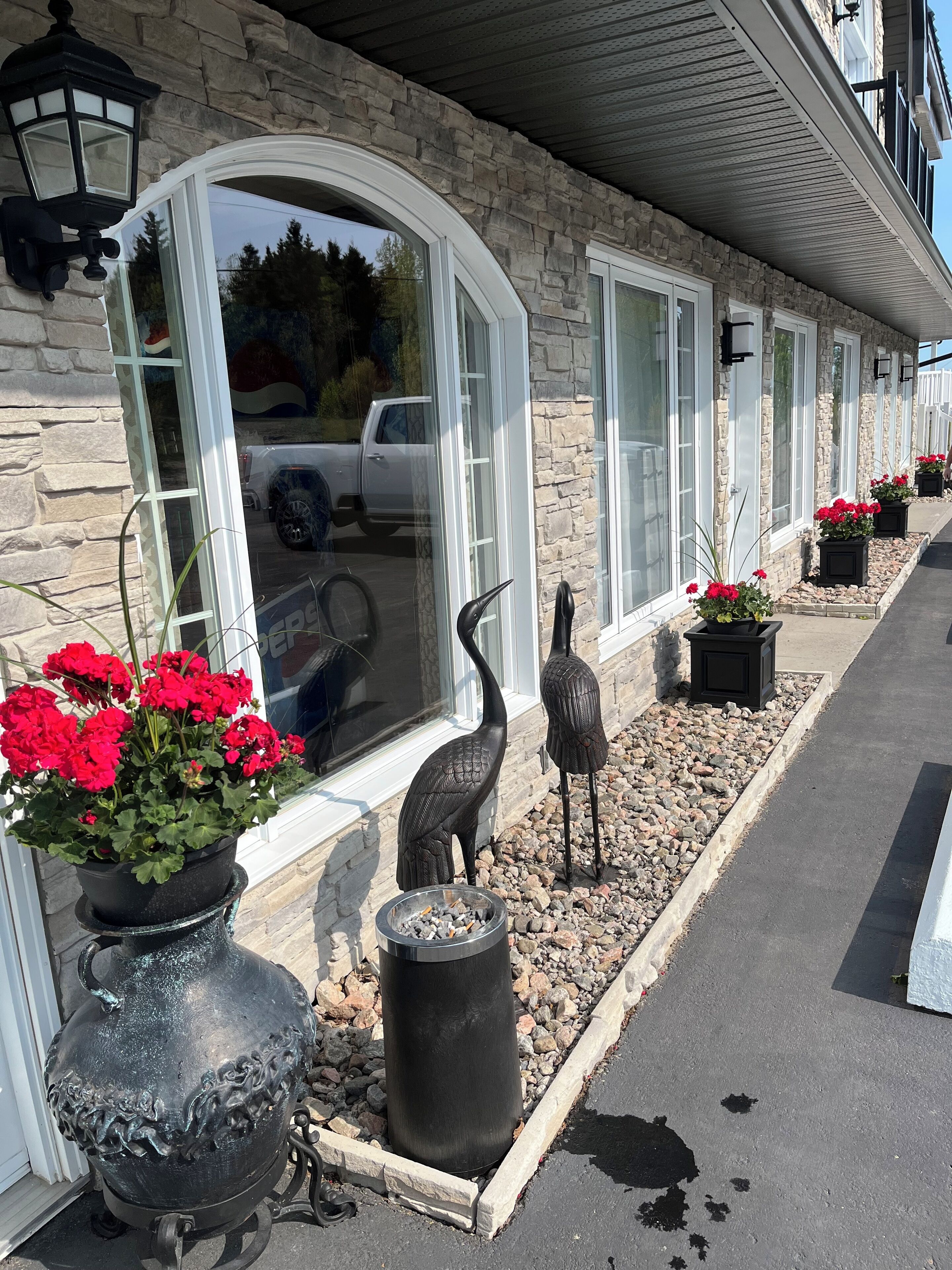 Un edificio de piedra con ventanas amplias, esculturas decorativas de pájaros y plantas en macetas.