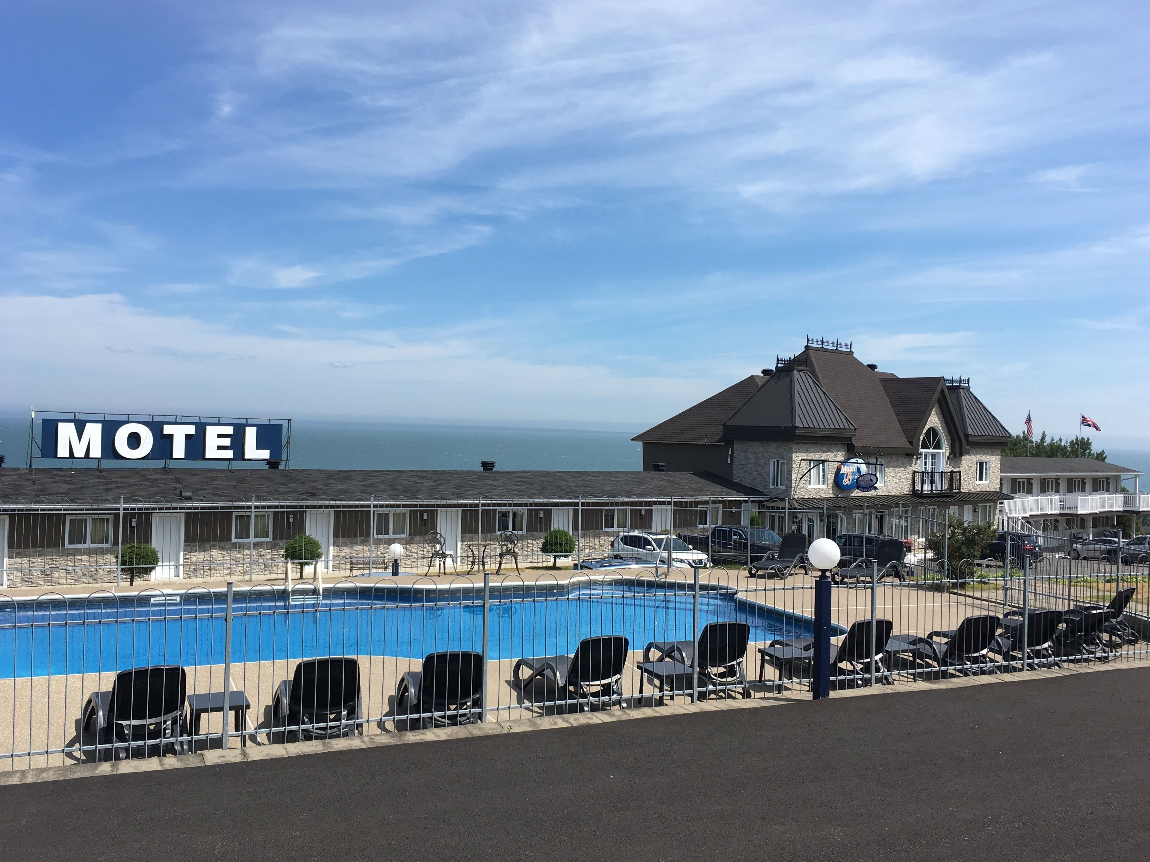 Un motel con piscina, zona de estar al aire libre y vista al océano.