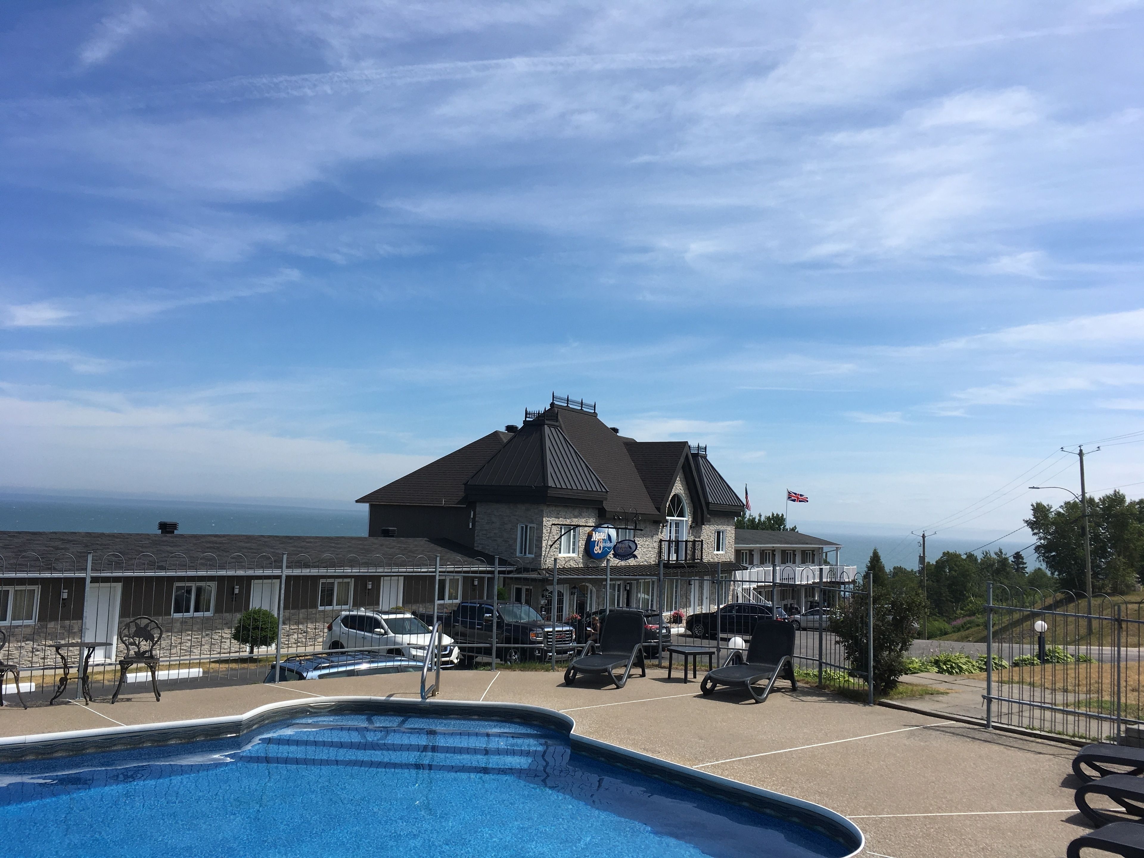 A hotel with a swimming pool, outdoor seating, and a view of the ocean.