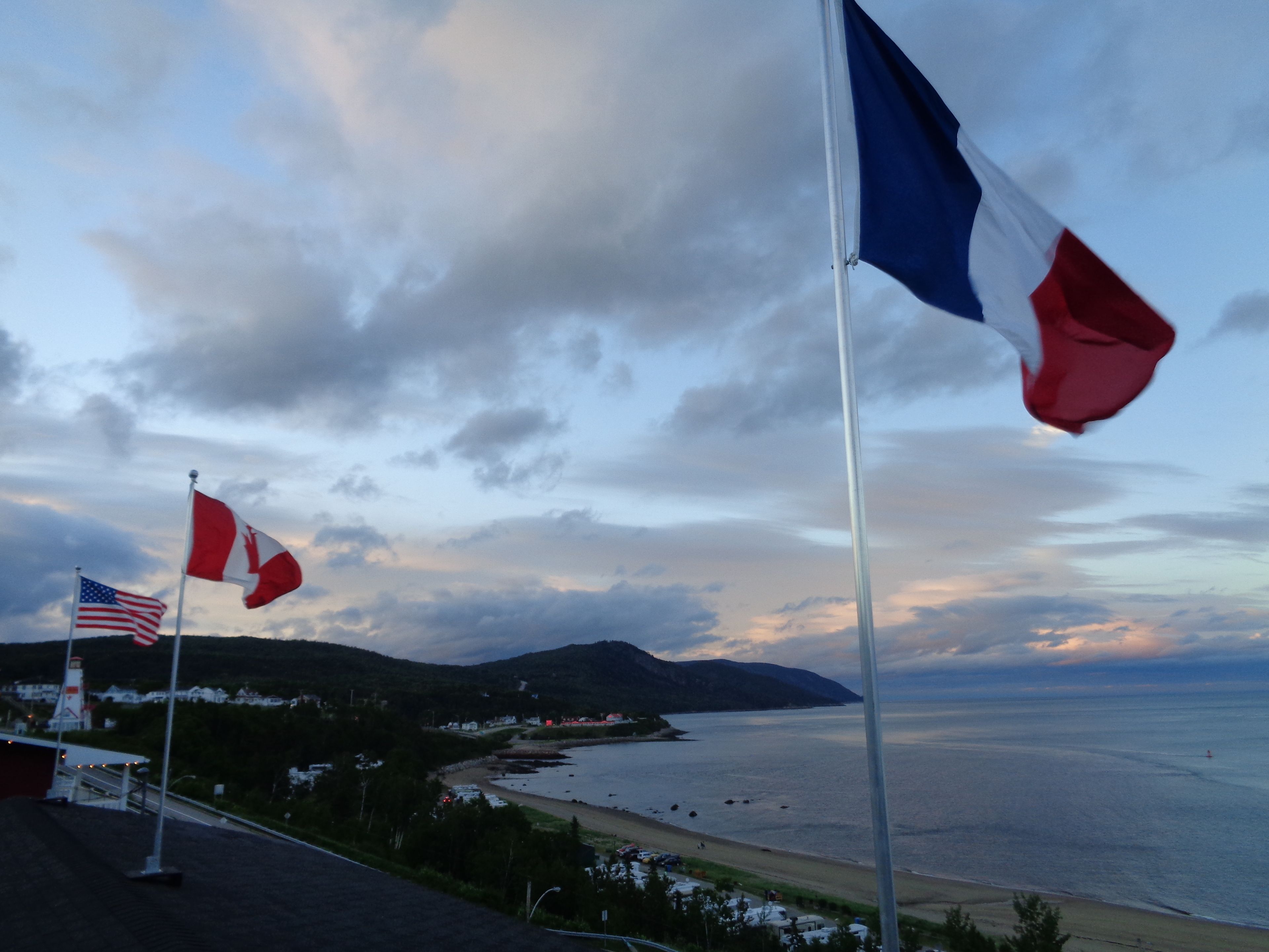 A coastal view with flags, including the American and Canadian flags, and a lighthouse in the background.