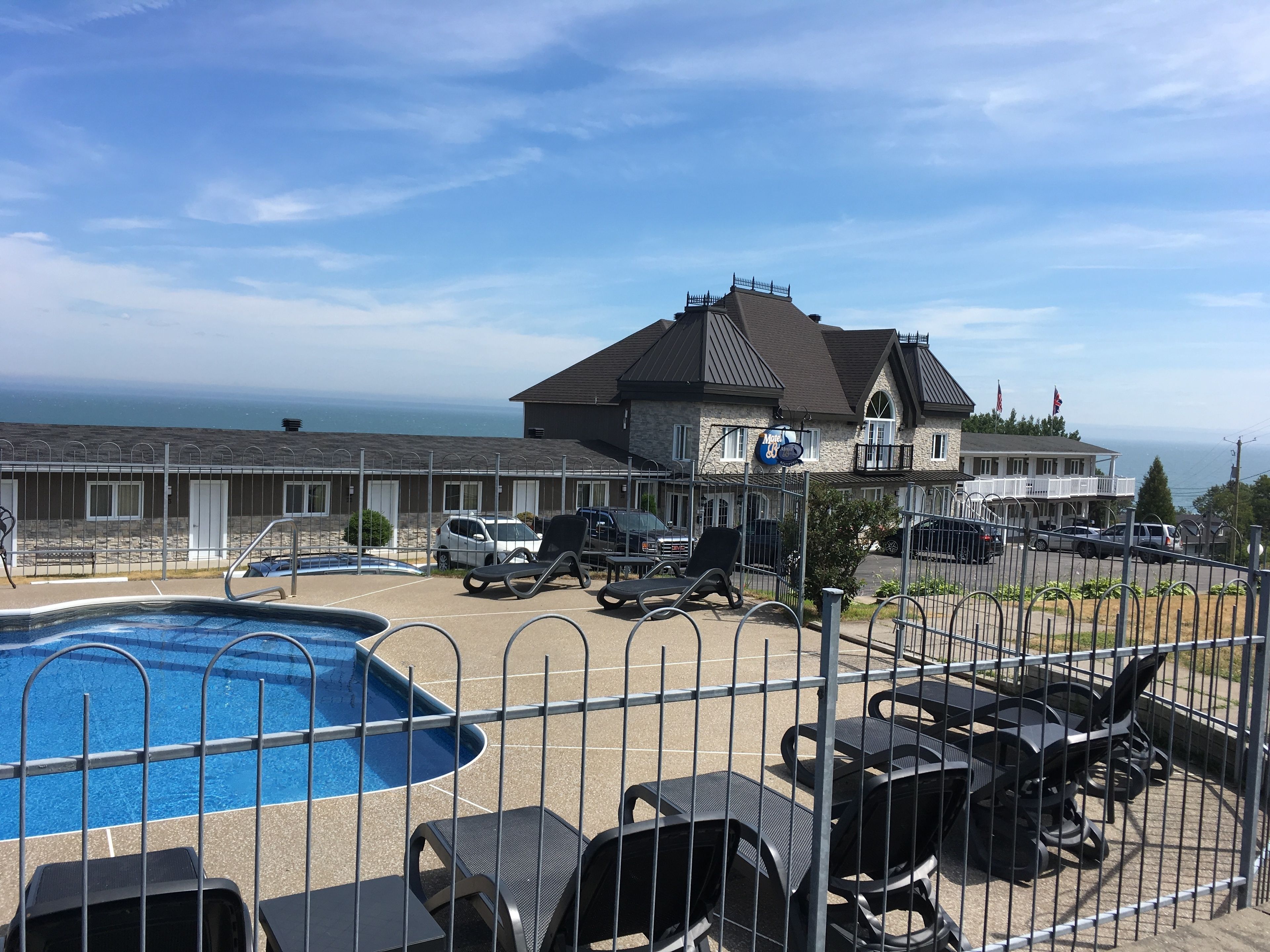 A hotel with a swimming pool, outdoor seating, and a view of the ocean.