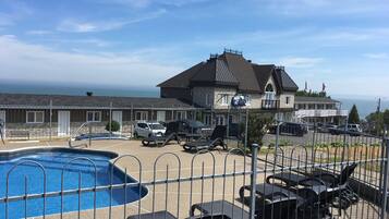 A hotel with a swimming pool, outdoor seating, and a view of the ocean.
