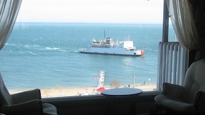 Um quarto com vista para o mar, um navio e uma praia.