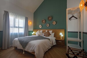 Una cama bien tendida con un edredón estampado, una mesita de noche con lámpara y decoración en la pared.