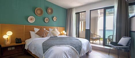 A hotel room with a large bed, bedside lamps, a wooden nightstand, and a view of the outdoor balcony.