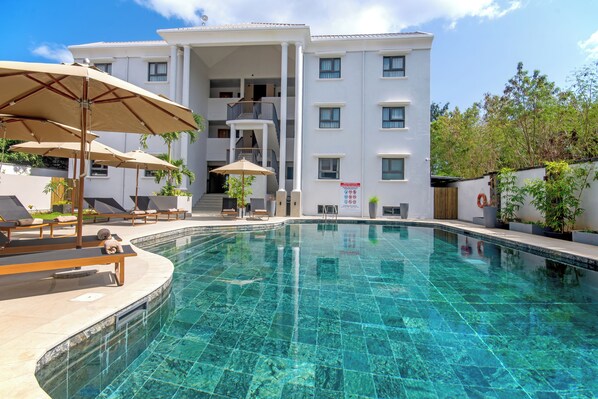 Una piscina al aire libre, sombrillas, tumbonas