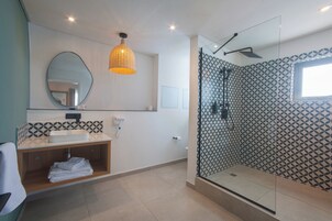 Un baño moderno con ducha envuelta en vidrio, tocador con lavabo y espejo sobre él.
