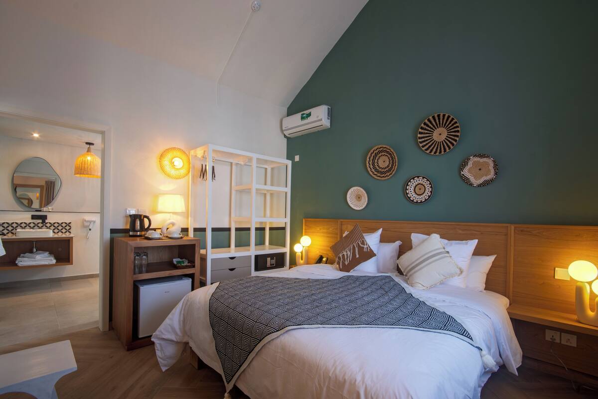 A bedroom with a bed, bedside tables, a desk, a mirror, and wall decorations.