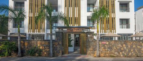 Un hotel moderno con fachada de piedra, amplias ventanas y un letrero que dice 'GDSUN Beach Hotel'.