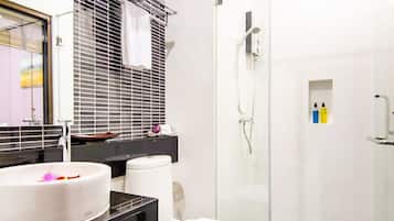 Ein modernes Badezimmer mit einer Duschkabine aus Glas, einem weißen Waschbecken und einer schwarzen Arbeitsplatte.