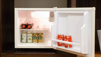 Un refrigerador abierto con bebidas y un recipiente pequeño.