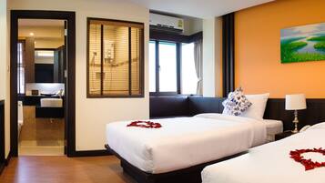 A hotel room with two beds, a TV, a desk, and a bathroom visible through an open door.