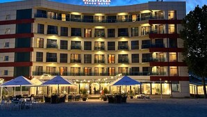 Ein mehrstöckiges Hotel mit Blick auf den Strand, Außenbereich zum Sitzen und einem Schild mit der Aufschrift 'Hawaii Beach Hotel'.