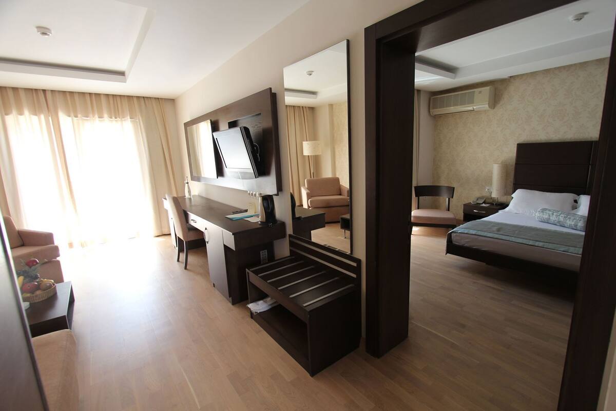 Une chambre d’hôtel équipée d’un lit, d’un bureau, d’une chaise, d’une télévision et d’un grand miroir.