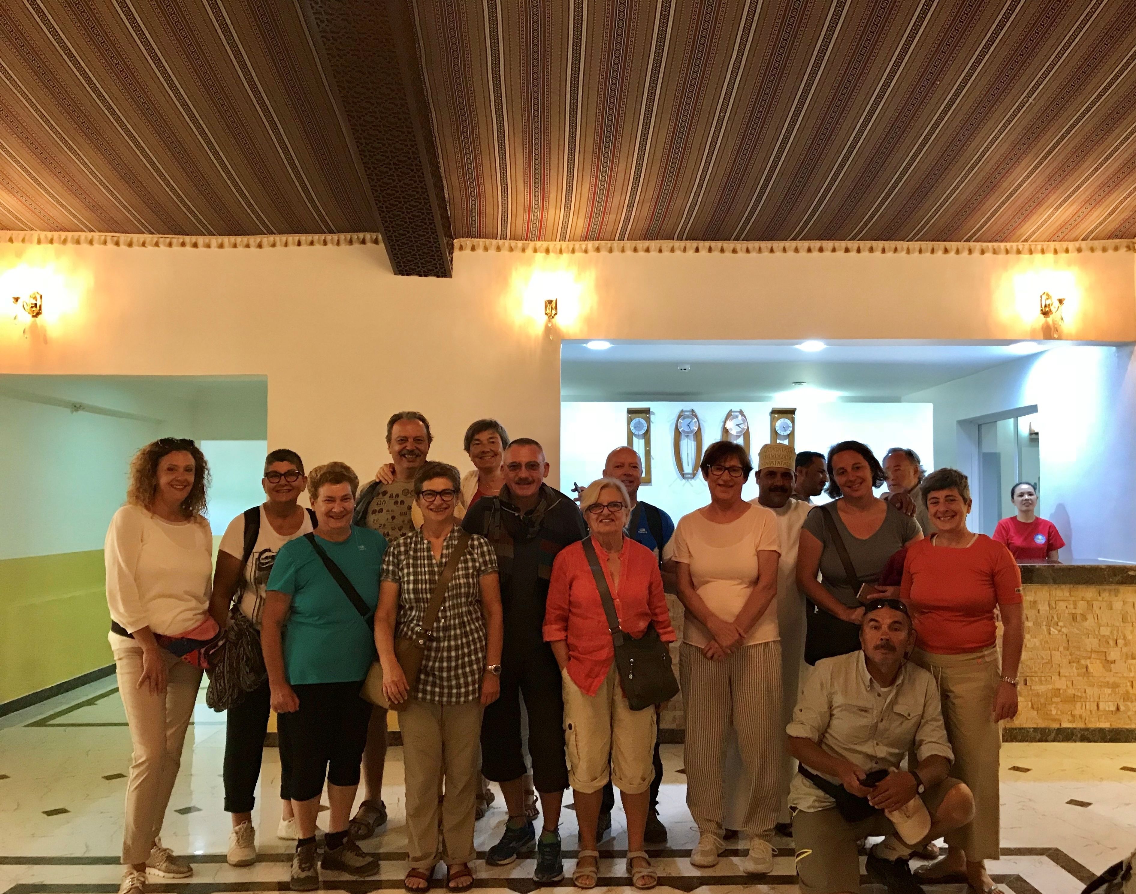 A group of people standing in a hallway with patterned ceiling and wall decorations.