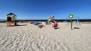 A beach with a lifeguard tower, inflatable slides, and a swing set.