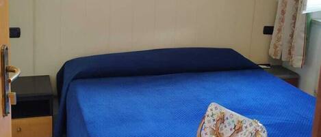 A room with a bed, a wall-mounted painting, a bedside table, and a door.