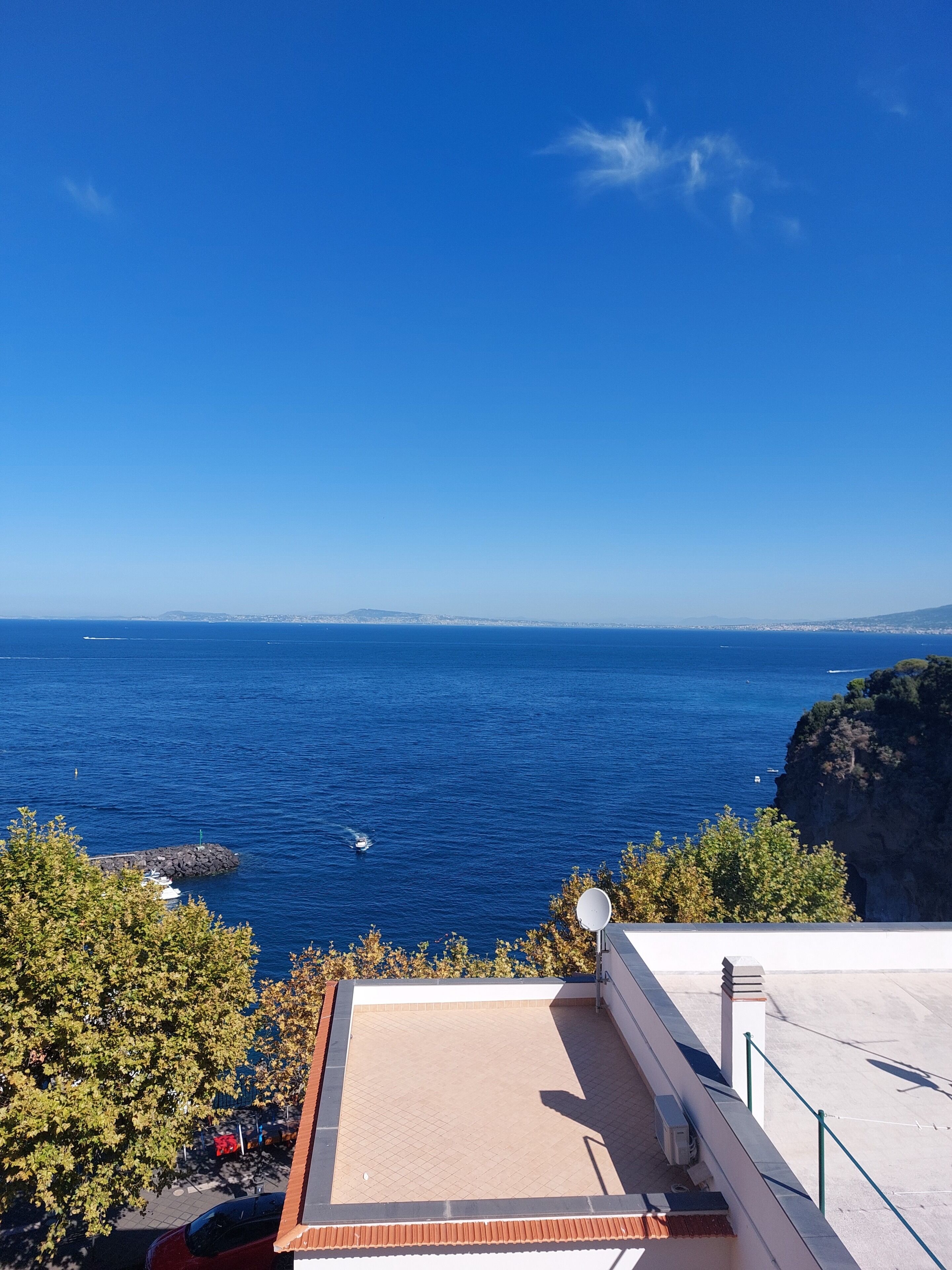 Une terrasse avec vue sur la mer, une antenne parabolique et une côte rocheuse.