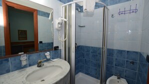 Een badkamer met een marmeren wastafel, een douchecabine van glas en een toiletbril met spuitfunctie.