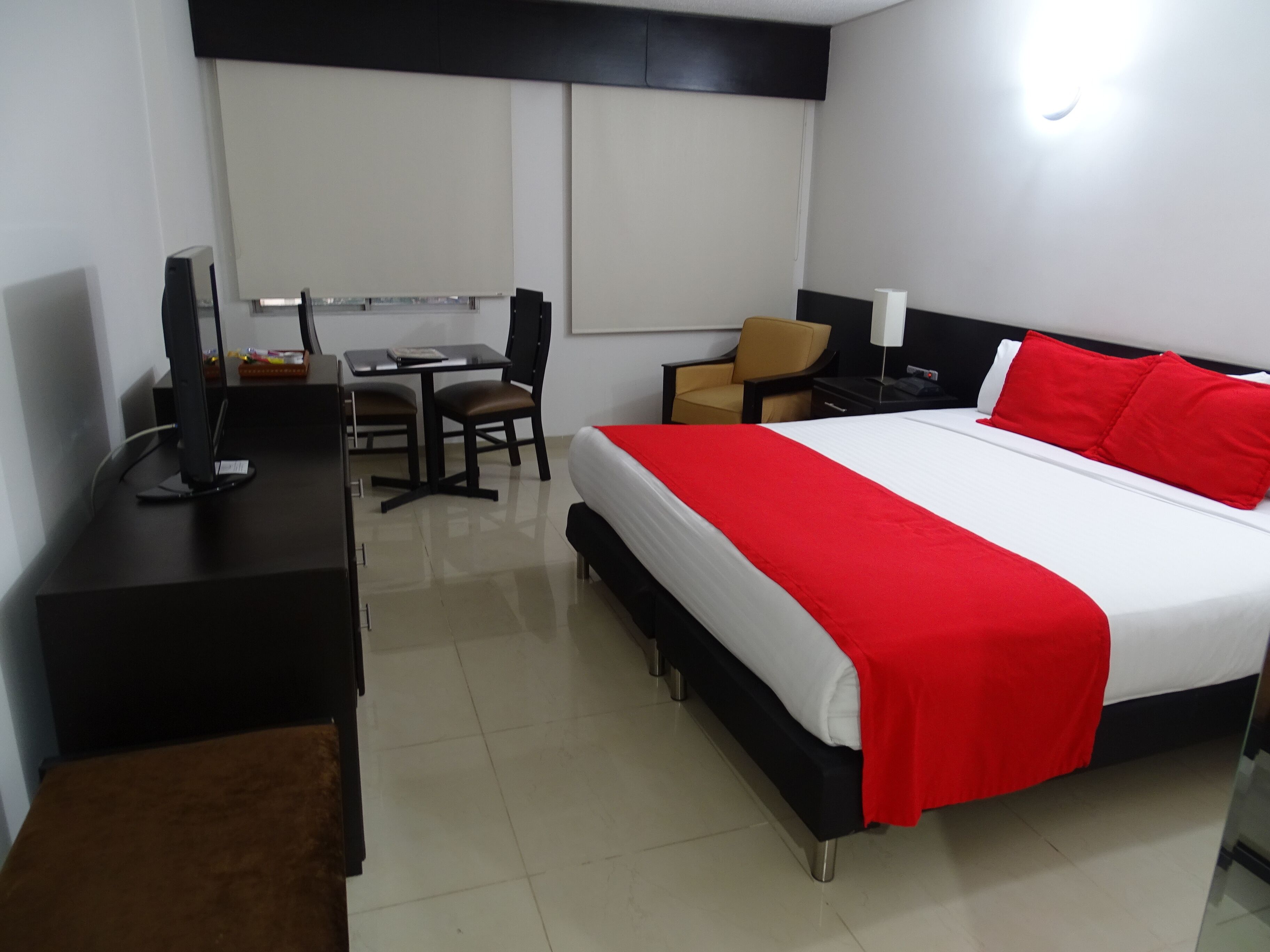 Una habitación de hotel con cama, escritorio, silla y televisor.