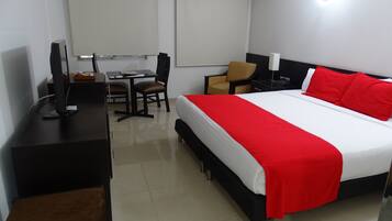 Una habitación de hotel con cama, escritorio, silla y televisor.