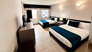 Camera d'albergo moderna con un letto grande, una scrivania e un computer. Due finestre offrono luce naturale e vista sulla città.
