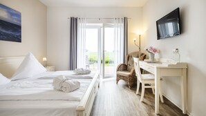 Habitación de hotel con cama, escritorio, silla, televisión y vistas al exterior.
