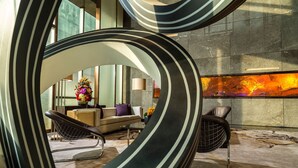 A modern lounge area with a curved wall design, a sofa, a chair, and a coffee table. - Four Seasons Hotel Shenzhen (Shenzhen)