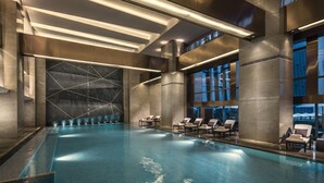 A modern indoor pool with geometric wall design, seating area, and large windows. - Four Seasons Hotel Shenzhen (Shenzhen)
