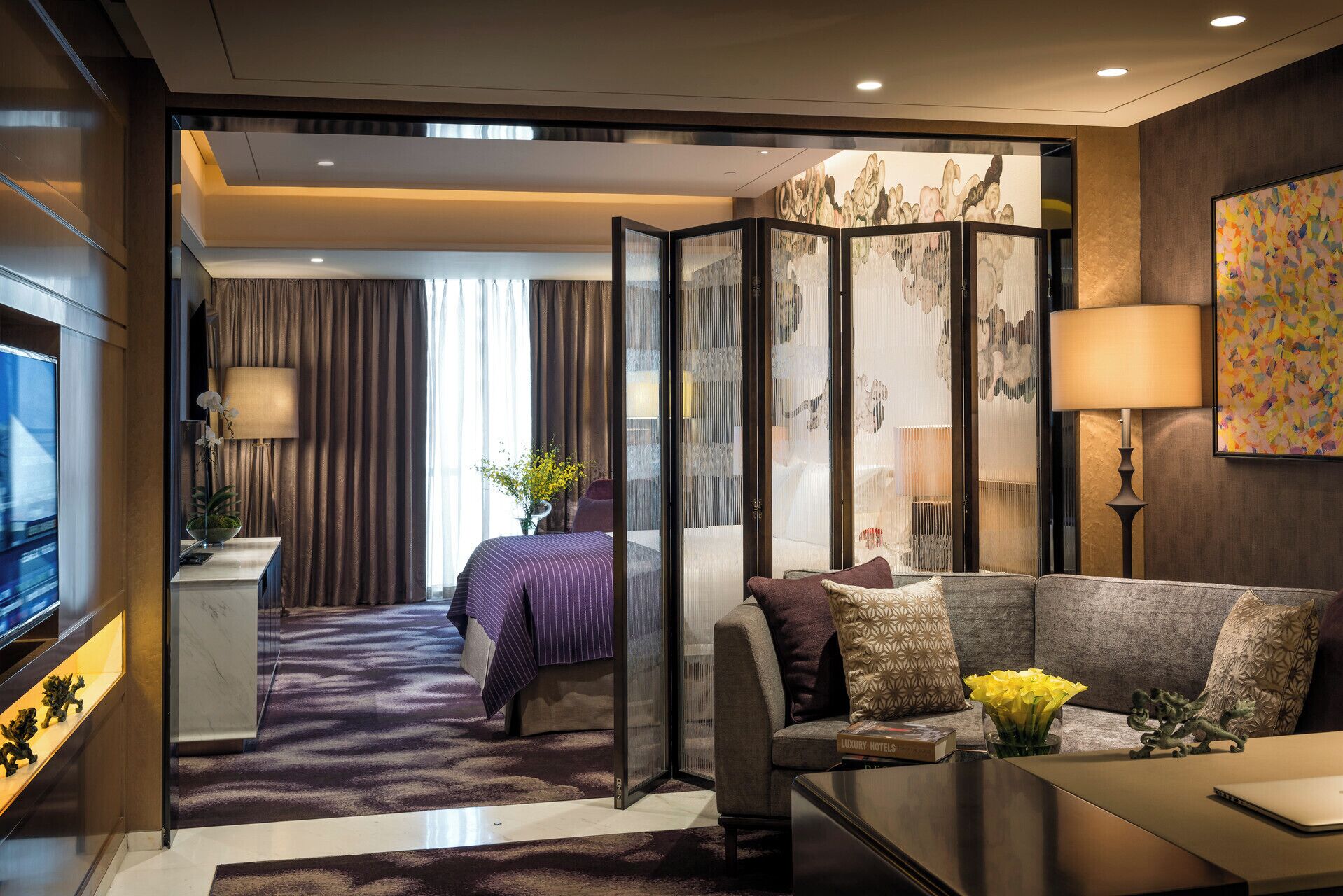 Una habitación de hotel moderna con una cama grande, un sofá, un escritorio y vistas a través de un separador.