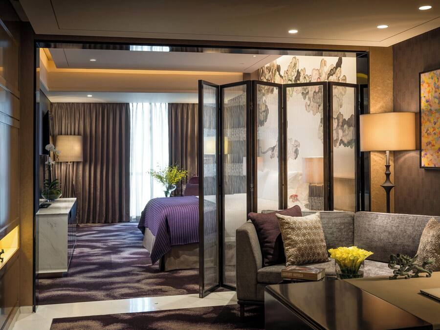 Una habitación de hotel moderna con una cama grande, un sofá, un escritorio y vistas a través de un separador.