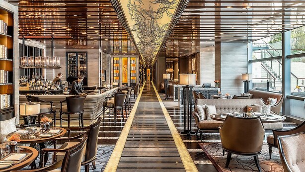 A long, narrow hotel lobby with a central walkway, seating areas on both sides, and a bar on the left. - Four Seasons Hotel Shenzhen (Shenzhen)