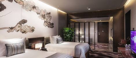 Habitación de hotel con dos camas, un mural grande en la pared, una planta y un televisor sobre un escritorio.