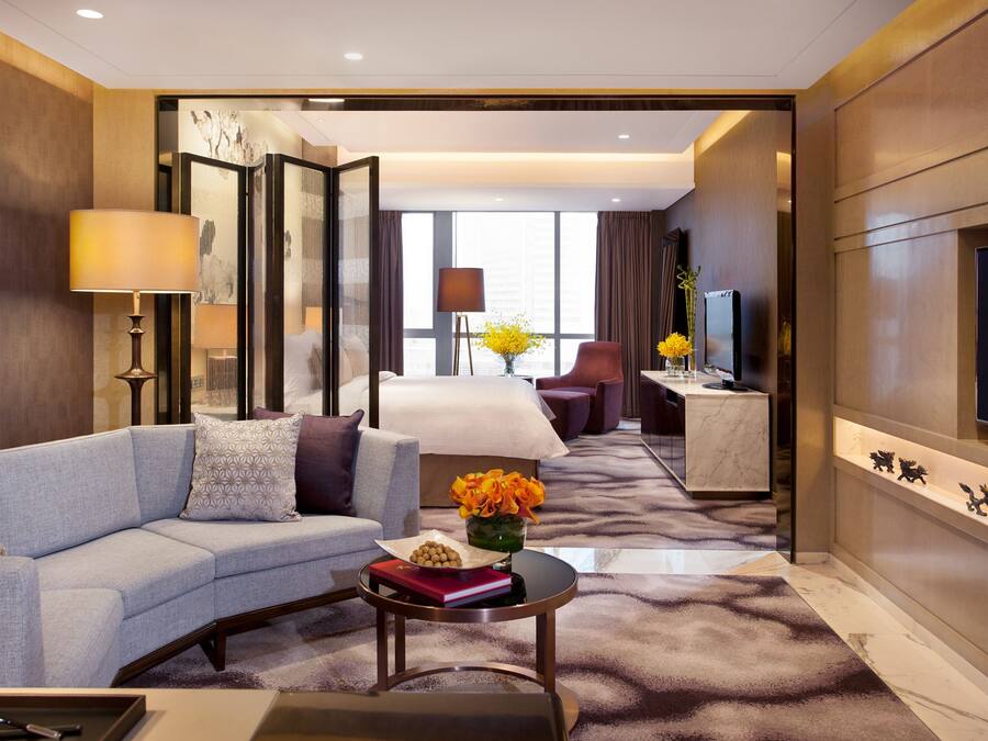 Una habitación de hotel moderna con sofá, mesa de centro y televisión.