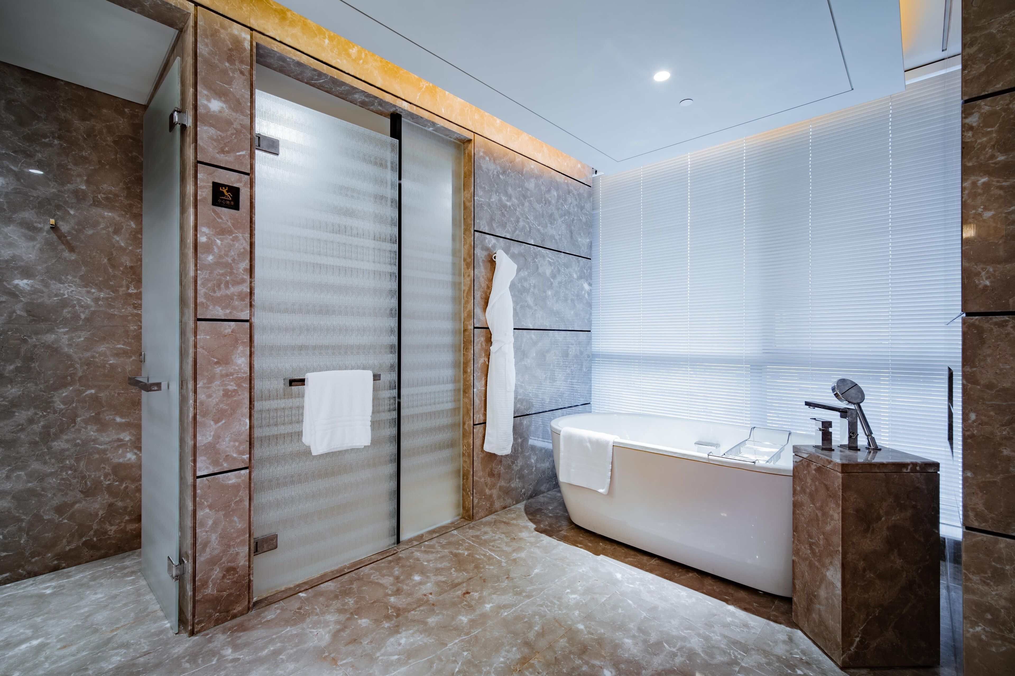 Une salle de bain moderne avec une douche à l’italienne en verre, une baignoire et un sol carrelé en marbre.