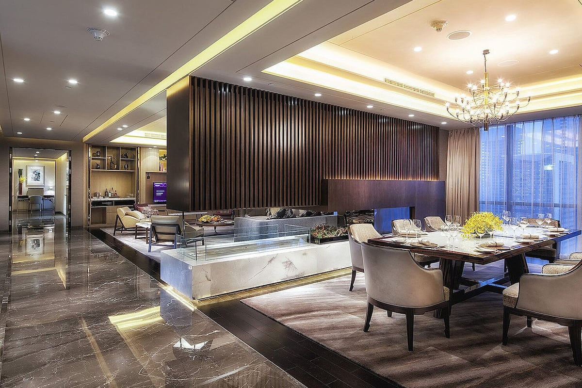 A modern dining area with a marble floor, a central island, and a chandelier.